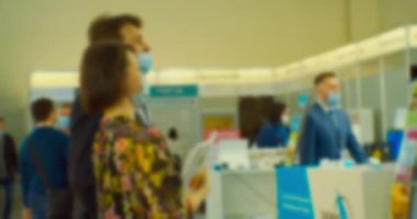 Bir iş temasının arka planı. Büyük, parlak bir salondaki bir iş toplantısında tezgahta iletişim kuran işadamlarının ve kadınların siluetleri bulanıklaştı.