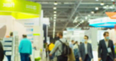 Büyük, parlak bir salonda, tanınmayan modern insanların bulanık siluetleri. Soyut iş geçmişi