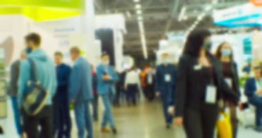 Büyük, parlak bir salonda, tanınmayan modern insanların bulanık siluetleri. Soyut iş geçmişi