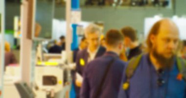 İş merkezinin içindeki büyük, parlak bir salonda birçok insan var. Bir iş temasının bulanık arkaplanı.