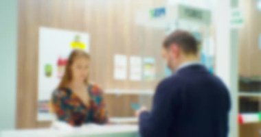 blurred silhouettes of businessmen man and woman who communicate at the counter at a business meeting in a large bright hall