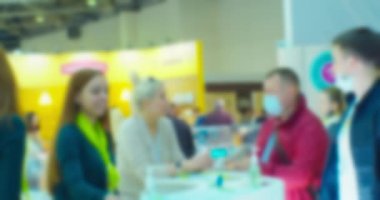 blurred silhouettes of businessmen man and woman who communicate at the counter at a business meeting in a large bright hall