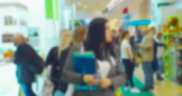 Blurry silhouettes of unrecognizable people in a large bright mall. Abstract business background — Stock Video