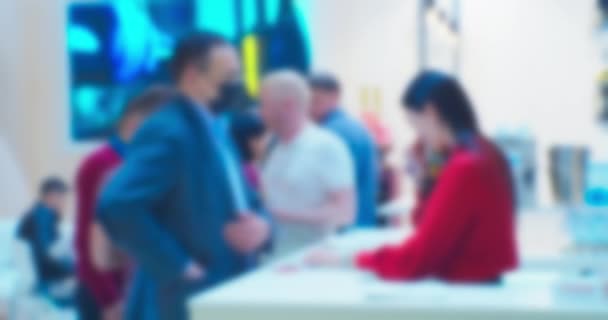 Blurred background on a business theme.unrecognizable people.modern man and woman communicate at the counter at a business meeting in a large bright hall — Stock Video