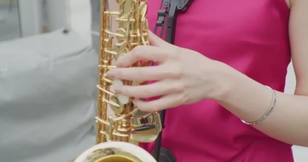 Nerozpoznatelná mladá žena v šatech hraje saxofonu.close-up — Stock video