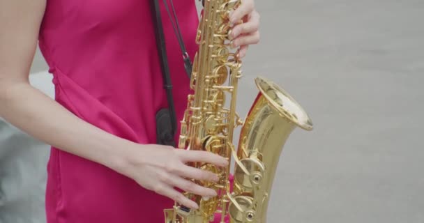 Onherkenbare jonge vrouw in een jurk speelt de saxofoon.close-up — Stockvideo