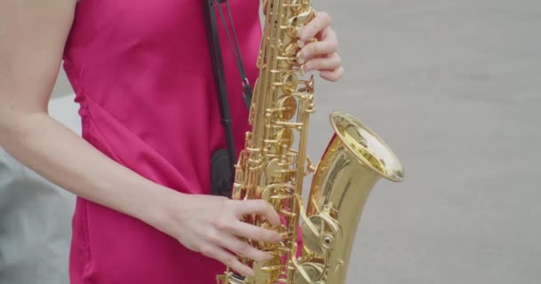 Oigenkännlig ung kvinna i klänning spelar saxofon.närbild — Stockvideo