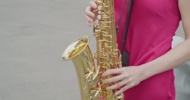 Onherkenbare jonge vrouw in een jurk speelt de saxofoon.close-up — Stockvideo