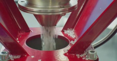 Yuvarlak gri plastik granüller zeplinden dökülüyor. Modern üretim. Plastik işleme ve üretimi. Yakın plan. Yüzeyin derinliği