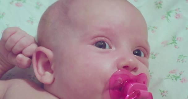 Słodkie nowonarodzone dziecko. portret malucha ze smoczkiem w ustach rozglądającego się z zaskoczeniem — Wideo stockowe