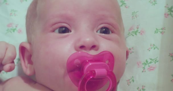 Cute little newborn baby. portrait of a toddler with a pacifier in his mouth. close-up — Stock Video