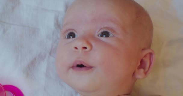 Portrait d'un mignon enfant allongé sur un drap levant les yeux dans la surprise — Video