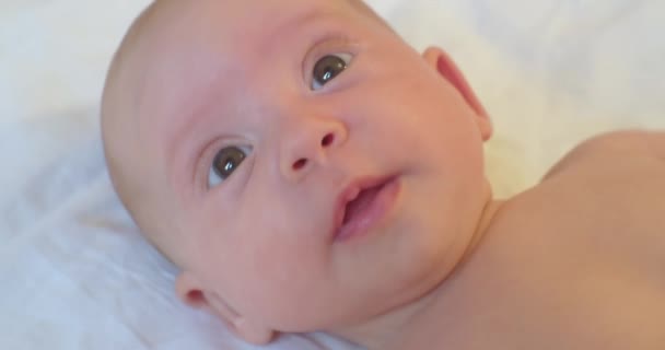 Portrait d'un mignon enfant allongé sur un drap levant les yeux dans la surprise — Video