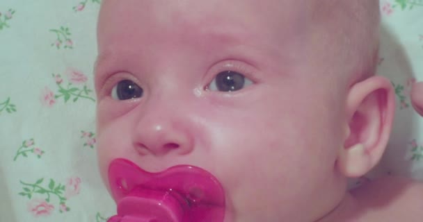 Funny portrait of a modern child.a cute little baby with a pink pacifier in his mouth looks surprised — Stock Video