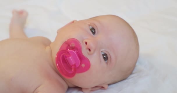 Portrait of a modern child.cute baby with a pacifier in his mouth lies in bed.view from above — Stock Video