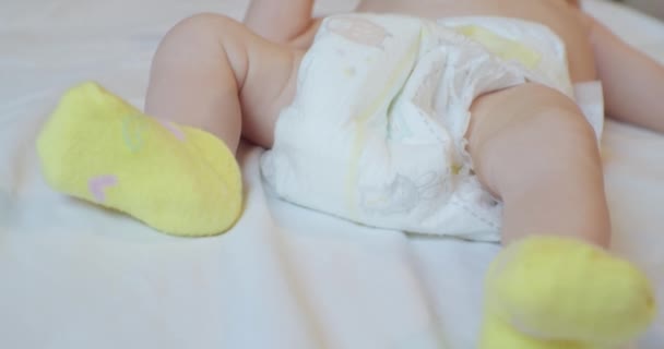 Unrecognizable baby in a diaper lying on bed sheet.closeup — Stock Video