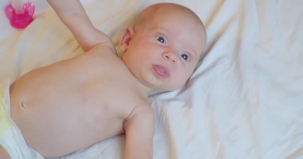 Retrato de um bebê bonito que se encontra em um lençol com um look.view surpreso de cima — Vídeo de Stock