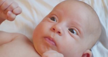 Şaşkın bakışlı sevimli komik bebek yatakta yatıyor. Portre. yakın plan