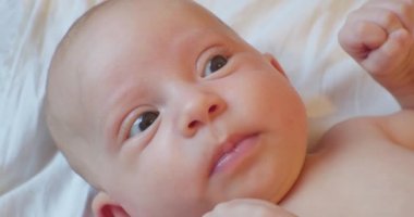 Şaşkın bakışlı sevimli komik bebek yatakta yatıyor. Portre. yakın plan