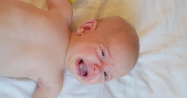 Modern bir çocuğun dikey portresi. Yatakta ağlayan şirin bir bebek. Yukarıdan görünüm