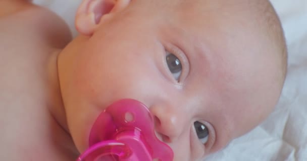 Portrait of a cute baby, who with a surprise look lies on the sheet.extreme close-up — Stok Video