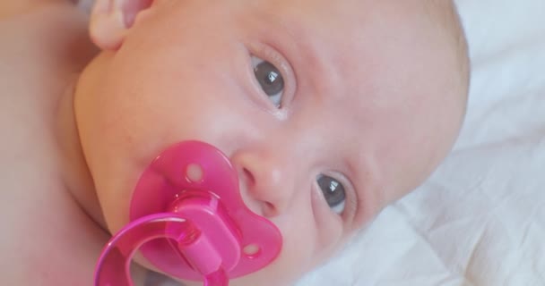 Портрет современного ребенка. милый младенец с пустышкой во рту лежит в постели. макро — стоковое видео