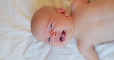 Modern bir çocuğun dikey portresi. Yatakta ağlayan şirin bir bebek. Yukarıdan görünüm