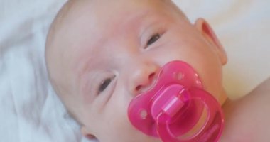 Ağzında pembe bir emzik olan şirin bir bebeğin portresi..