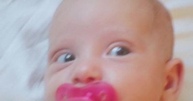 Şaşkın bakışlı sevimli komik bebek yatakta yatıyor. Portre. yakın plan