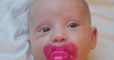 Şaşkın bakışlı küçük bir çocuk çarşafta yatıyor. Yakın plan.