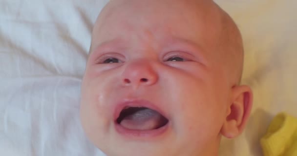 Retrato de um bebê chorando.uma criança pequena encontra-se na cama.close-up — Vídeo de Stock