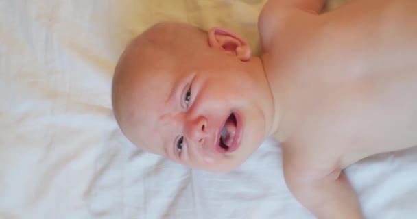 Verticale video.ritratto di un bambino moderno.bambino carino che piange sdraiato a letto. vista dall'alto — Video Stock