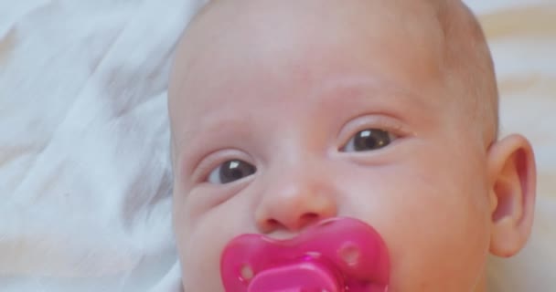 Cute funny baby with surprised look lies in bed. portrait. close-up — Stock Video