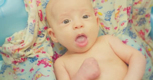 Küçük sevimli bebek banyo yapıyor, parlak bir çarşafın üzerinde yatıyor. Yakın plan. — Stok video