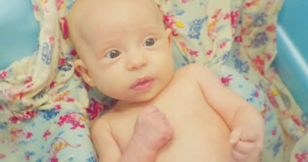 Маленький милый смешной ребенок принимает ванну лежа на ярком sheet.portrait.close-up — стоковое видео