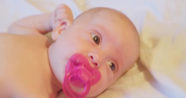 Liten söt rolig bebis med rosa napphållare i munnen. närbild porträtt — Stockvideo