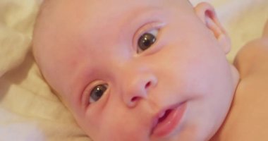 Yatağında yatan ve şaşkınlıkla kafasını kaldıran küçük sevimli bir çocuğun portresi. yakın plan