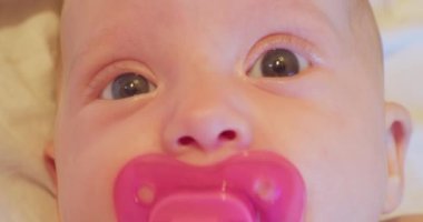 Küçük, komik ve sevimli bir bebeğin yüzü. Emziği var ve şaşırmış görünüyor. yakın plan portre