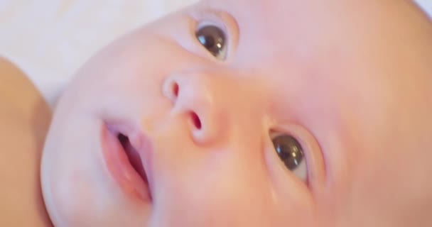 Porträtt av en söt liten bebis som ligger i sängen. närbild. vy ovanifrån — Stockvideo