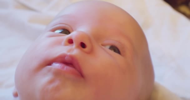 Retrato de un bebé lindo. El rostro de un niño pequeño acostado en la cama — Vídeo de stock