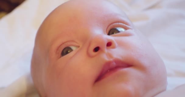 Egy aranyos baba portréja. Egy kisgyerek arca fekszik az ágyban. — Stock videók