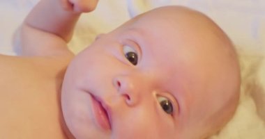 Yatağında yatan ve şaşkınlıkla kafasını kaldıran küçük sevimli bir çocuğun portresi. yakın plan