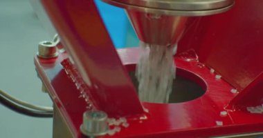 Modern teknoloji ve üretim. Plastik işleniyor. Yuvarlak gri plastik topaklar zıpzıpzıptan düşer. Yakın plan. Yüzeyin derinliği