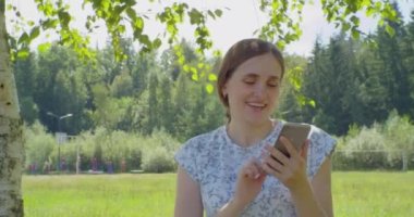 Elinde akıllı telefon olan güzel bir genç kadın. Açık havada yaz portresi.