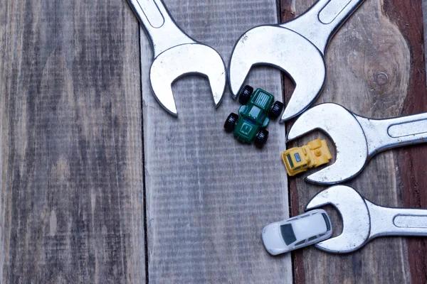 Little toy cars near the wrenches on a wooden surface. — Stock Photo, Image