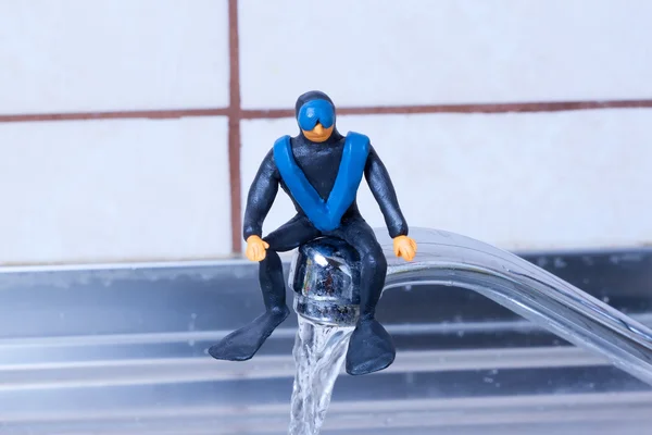 Little diver sitting on tap kitchen faucet. — Stock Photo, Image