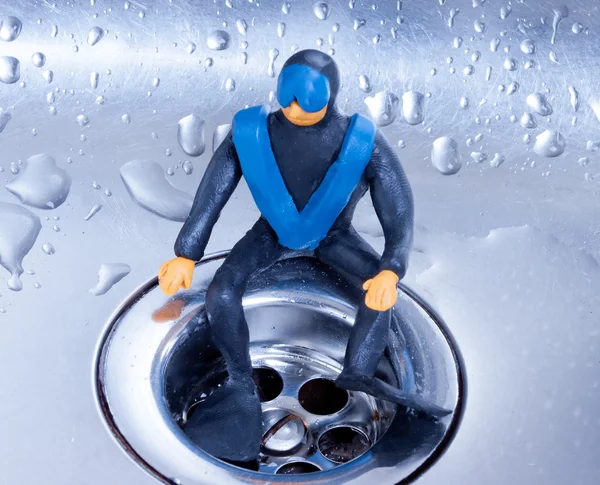 Small plasticine diver sitting on a steel sink — Stock Photo, Image