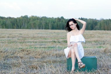 eski bir bavula oturan kısa elbiseli güzel kız