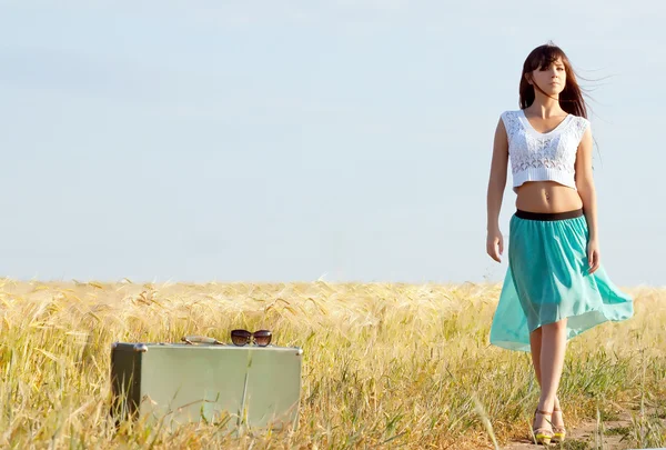 kulakları olan bir arka plan alana bavula ile poz genç güzel uzun saçlı kız. Önden Görünüm.