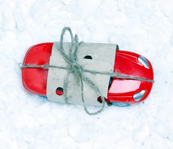 Speelgoedauto verpakt als een geschenk voor kunstmatige sneeuw. — Stockfoto